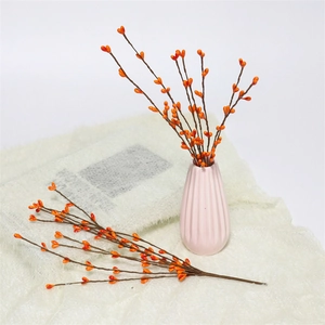 Artificial orange berry branches in a pink striped ceramic vase for home decoration