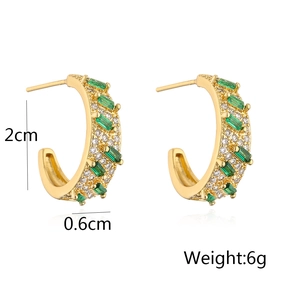 Detail view of C-shaped gold earrings with green rectangular zircon and white pave stones