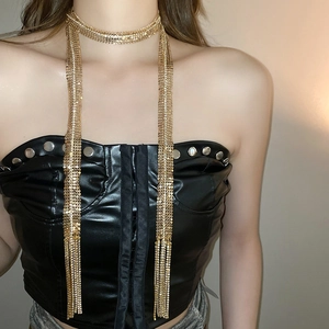 Detail view of a gold glitter mesh body chain with fringe tassels on a black leather outfit