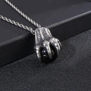 Close-up of punk dragon claw pendant holding black bead on stainless steel chain