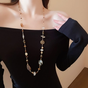 Dettaglio di una collana lunga con perle di marmo e agata su una modella elegante