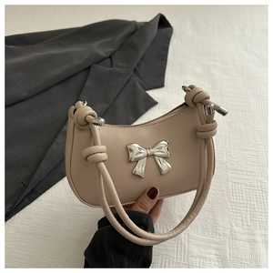 Detail of beige hobo bag with silver metal bow and stylish knotted shoulder strap