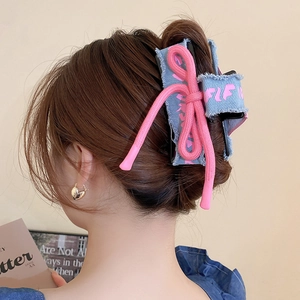 Detail of denim bow hair claw clip with pink drawstring knot on model's hairstyle