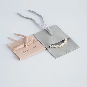 Close-up of pink and grey microfiber jewelry pouches with soft suede texture and logo