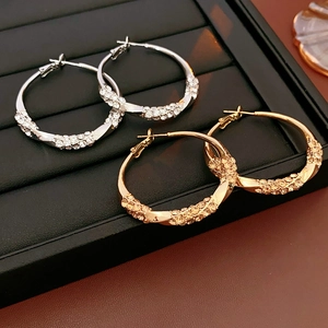 Macro shot of twisted metal hoop earrings with sparkling rhinestones on black display
