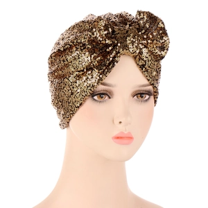 Detailed close-up of golden sequin turban hat with a large bow on white background