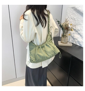 Detailed view of light green nylon crossbody bag featuring stylish pleated drawstring design