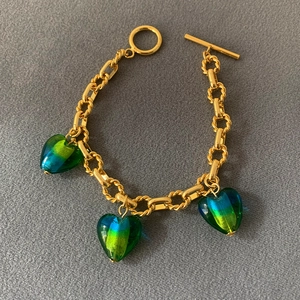 Detail of gold chain bracelet with three emerald and blue heart glass pendants and OT clasp
