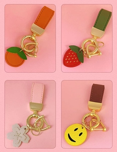 Detail of colorful PU leather keychains with fruit and flower charms on pink background