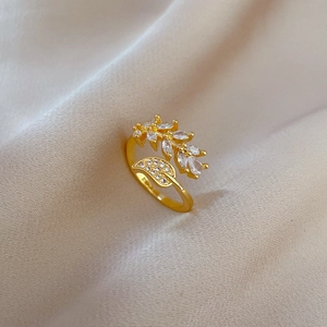 Macro shot of gold leaf ring with white zircon stones on beige textured fabric