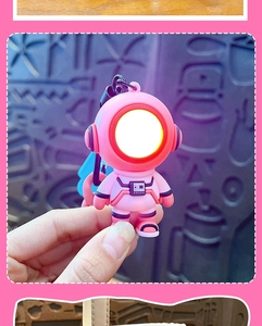 Close-up of pink astronaut keychain with glowing LED light face