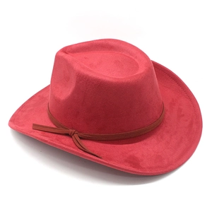 Détail d'un chapeau de cowboy rouge en suédine avec une sangle en cuir brun sur le côté
