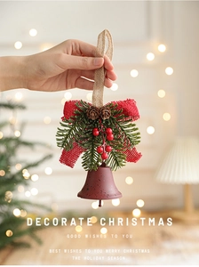 Detail of metal Christmas bell with pine needles, red berries and a burlap bow ornament