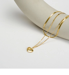 Macro view of gold heart pendant with beaded edges on a sleek dual-layered snake chain