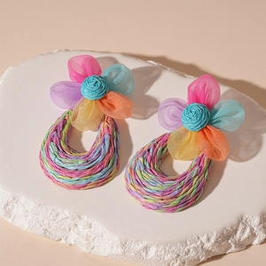 Detail of handmade raffia hoop earrings with colorful lace mesh flowers and bohemian textures