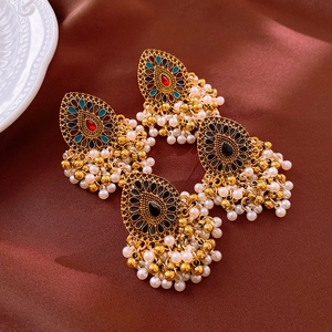 Detailed macro view of vintage Jhumka earrings with tassels on silk fabric