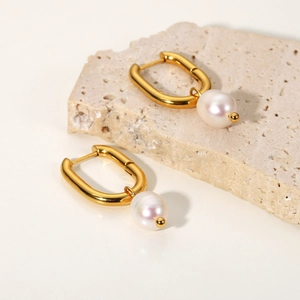 Detail of elegant gold U-shaped earrings with natural freshwater pearl pendants