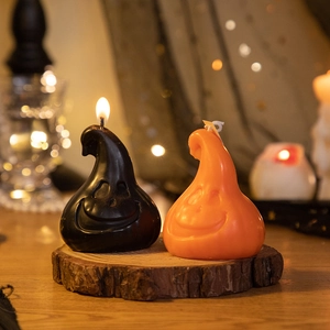 Ghost-shaped Halloween scented candles in black and orange on a rustic wood base