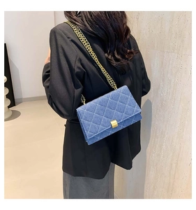 Detail view of denim blue quilted shoulder bag with gold chain and metal lock