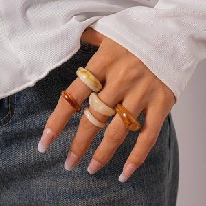 Close-up of colorful resin acrylic rings in amber and marble white on a model's hand