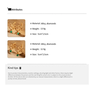 Detailed view of gold snake earrings with green waterdrop pendants and diamond accents