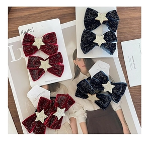 Detailed macro view of sequined velvet bow hair clips with golden star charm accents