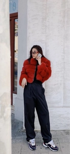 Detailed view of red faux fur coat with horizontal stitching and plush texture