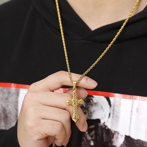 Close-up of gold-colored cross pendant with twisted rope chain on black hoodie