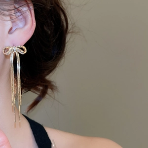 Detail von eleganten Gold-Schleifenohrringen mit Zirkonia-Quasten an einem Model