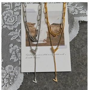 Macro shot of layered V-shaped pendant necklaces with paperclip chains in gold and silver