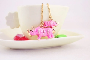 Detail of pink enamel rhino charms with gold finish and crystals on necklace chains