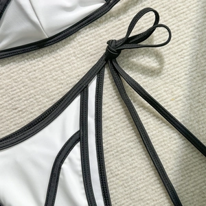 Detail shot of black and white bikini side ties with contrast piping and bow design