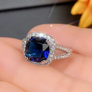 Close-up of elegant silver ring featuring square blue gemstone and pavé diamonds