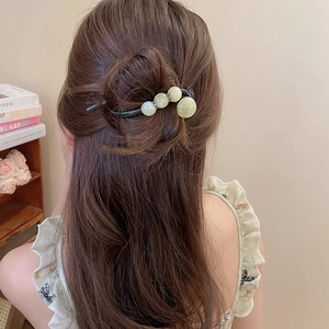 Detailansicht einer schwarzen Haarspange mit grünen Strasssteinen am Haar des Modells