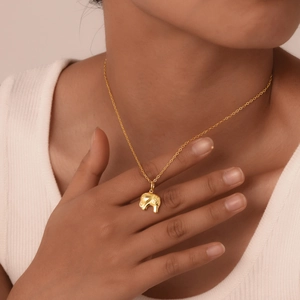 Close-up of a gold-plated elephant pendant necklace with intricate patterns on a model