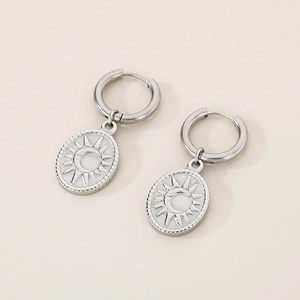 Close-up of silver celestial earrings with sun and moon relief on oval pendant charm