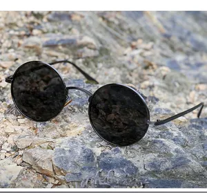Detail of vintage round punk sunglasses with black metal frame on a rock background