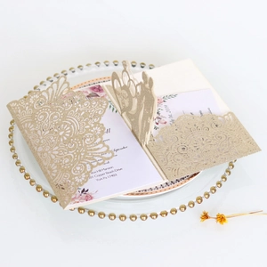 Detail of 3D laser-cut golden glitter wedding invitation with pop-up carriage and lace pattern