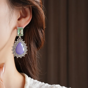 Détail de boucles d'oreilles vintage avec pierres violettes et vertes et diamants blancs