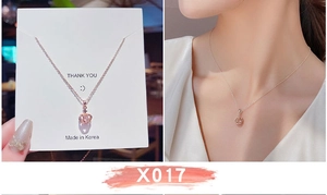 Macro della collana con ciondolo a corona in oro rosa con cristallo su modella e carta