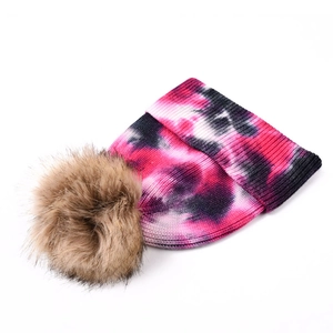 Détail du bonnet en tricot tie-dye épais avec un grand pompon en fausse fourrure douce