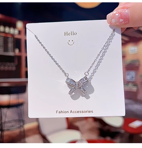 Gros plan d'un collier nœud en argent serti de zircons sur une carte de présentation