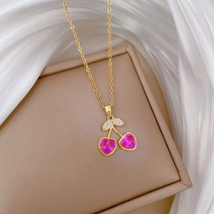 Detail of pink heart crystal cherry pendant with gold leaves on silk background