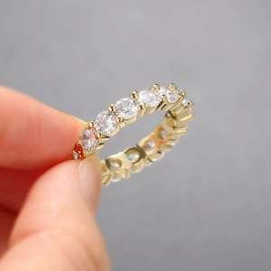 Detailed view of hand holding a gold eternity ring with 4mm round-cut cubic zirconia stones