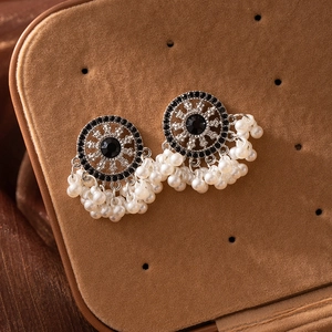 Macro shot of ethnic pearl tassel earrings with black stones on a brown velvet box