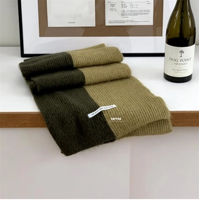 Close-up of olive green and khaki knit scarf featuring stylish text labels and soft texture