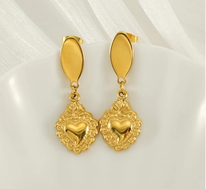 Detailed macro view of vintage golden sacred heart earrings on elegant shell tray