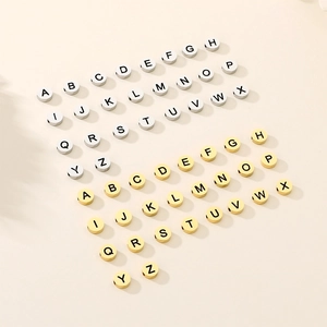 Flat lay of gold and silver metal alphabet beads for DIY jewelry making and bracelet design