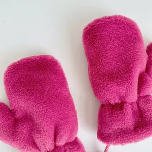 Detailed texture of bright pink plush mittens with neck cord for winter warmth