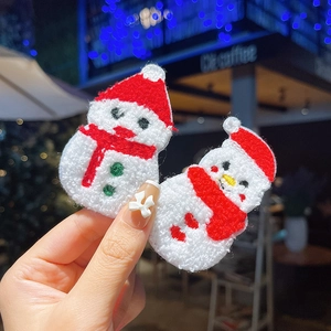 Detail of plush snowman Christmas hair clips with knitted texture held in hand